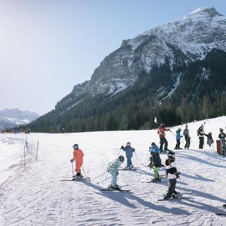 Des enfants skient sur une pente enneigée dans les Grisons. [Keystone - Christian Beutler]