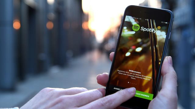 Un homme utilisant Spotify sur son smartphone. [Keystone - DPA/Britta Pedersen]