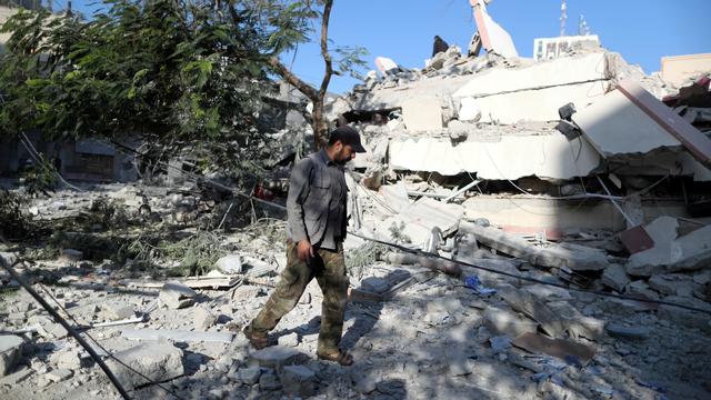 Un Palestinien marchant près des ruines d'un bâtiment détruit par des frappes israéliennes. [Reuters - Suhaib Salem]