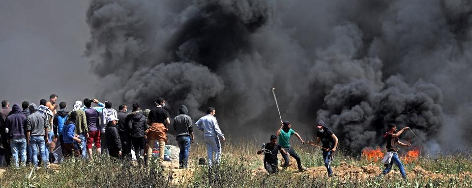 Des manifestants palestiniens jettent des pierres en direction des soldats israéliens, ce 6 avril 2018, à la frontière Gaza-Israël. [EPA - MOHAMMED SABER]