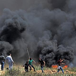 Des manifestants palestiniens jettent des pierres en direction des soldats israéliens, ce 6 avril 2018, à la frontière Gaza-Israël. [EPA - MOHAMMED SABER]