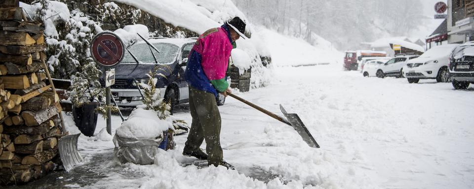 Une personne déblaie de la neige à Zinal, dimanche 21 janvier. [Keystone - Jean-Christophe Bott]