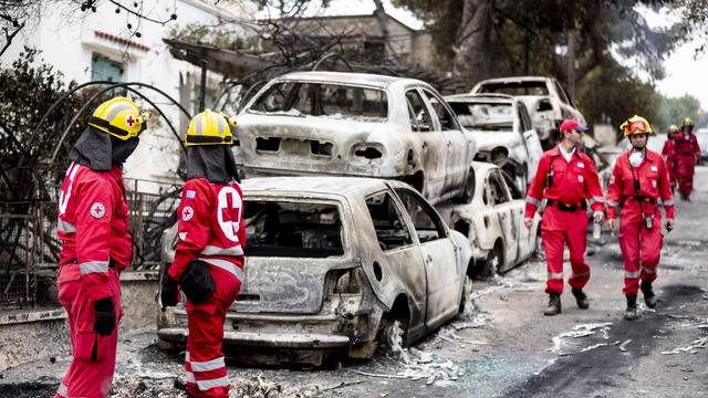 Des secouristes dans les rues de la ville de Mati, près d'Athènes, ravagée par les incendies. [DPA/AFP - Christoph Soeder]