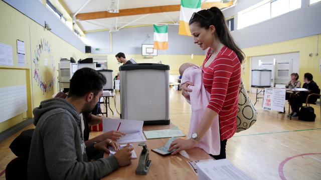 Une femme et son bébé dans un bureau de vote à Dublin, le 25 mai 2018. Les Irlandais votent sur la suppression de l'interdiction de l'avortement, dans un référendum historique. [Keystone - Max Rossi]