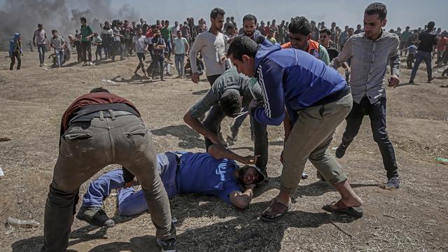 Des manifestants palestiniens tentent d'aider un manifestant blessé lors d'affrontements près de la frontière avec Israël dans l'est de la bande de Gaza, 14 mai 2018 [Keystone - MOHAMMED SABER]