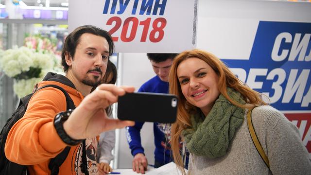 Des personnes prennent un selfie dans un centre de collecte de signatures pour la candidature de Vladimir Poutine aux élections 2018. [Sputnik/AFP - Evgeny Biyatov]