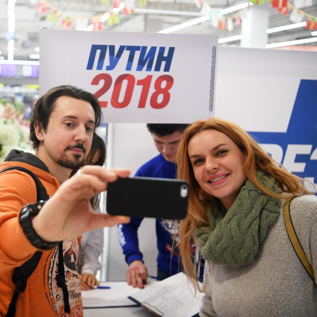 Des personnes prennent un selfie dans un centre de collecte de signatures pour la candidature de Vladimir Poutine aux élections 2018. [Sputnik/AFP - Evgeny Biyatov]