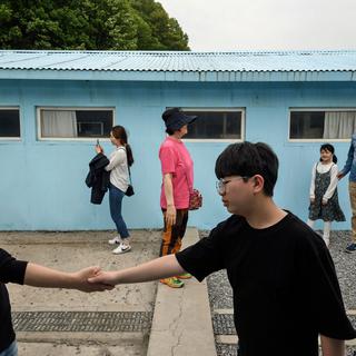 Les visiteurs viennent reproduire la célèbre poignée de main entre les deux présidents coréens, par-dessus la ligne de démarcation. [AFP - Ed Jones]