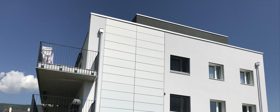 Des panneaux solaires appliqués sur un bâtiment de logements à Boudry (NE). [Solaxess]