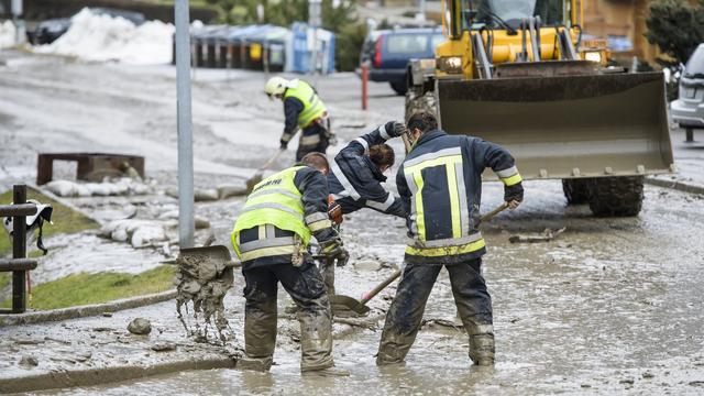 Des pompiers déblaient la route recouverte d'une coulée de boue, le 22 janvier 2018 à Champéry (VS). [Jean-Christophe Bott - Keystone]