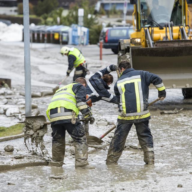 Des pompiers déblaient la route recouverte d'une coulée de boue, le 22 janvier 2018 à Champéry (VS). [Jean-Christophe Bott - Keystone]