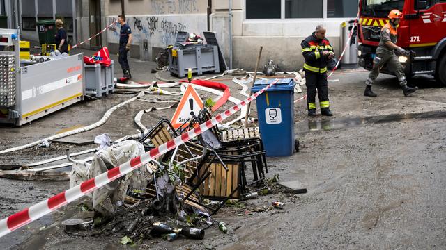 Des pompiers nettoyant les dégâts à la rue du Petit-Saint-Jean. [Keystone - Jean-Christophe Bott]