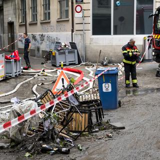 Des pompiers nettoyant les dégâts à la rue du Petit-Saint-Jean. [Keystone - Jean-Christophe Bott]