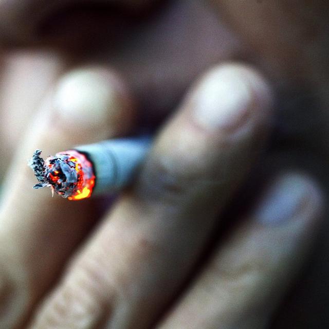 Une personne tire sur sa cigarette. [Keystone - Christophe Schmidt]