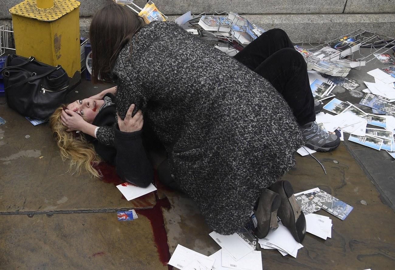 Une passante vient en aide à une femme blessée lors de l'attentat sur le pont de Westminster à Londres, en mars 2017. [Reuters - Toby Melville]