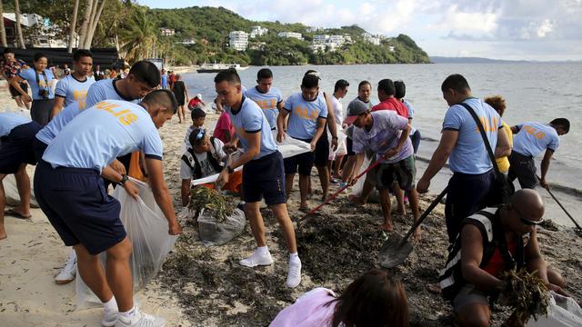 Policiers et riverains lors d'une opération de nettoyage des plages fin avril à Boracay, aux Philippines. [AP/Keystone - Aaron Favila]