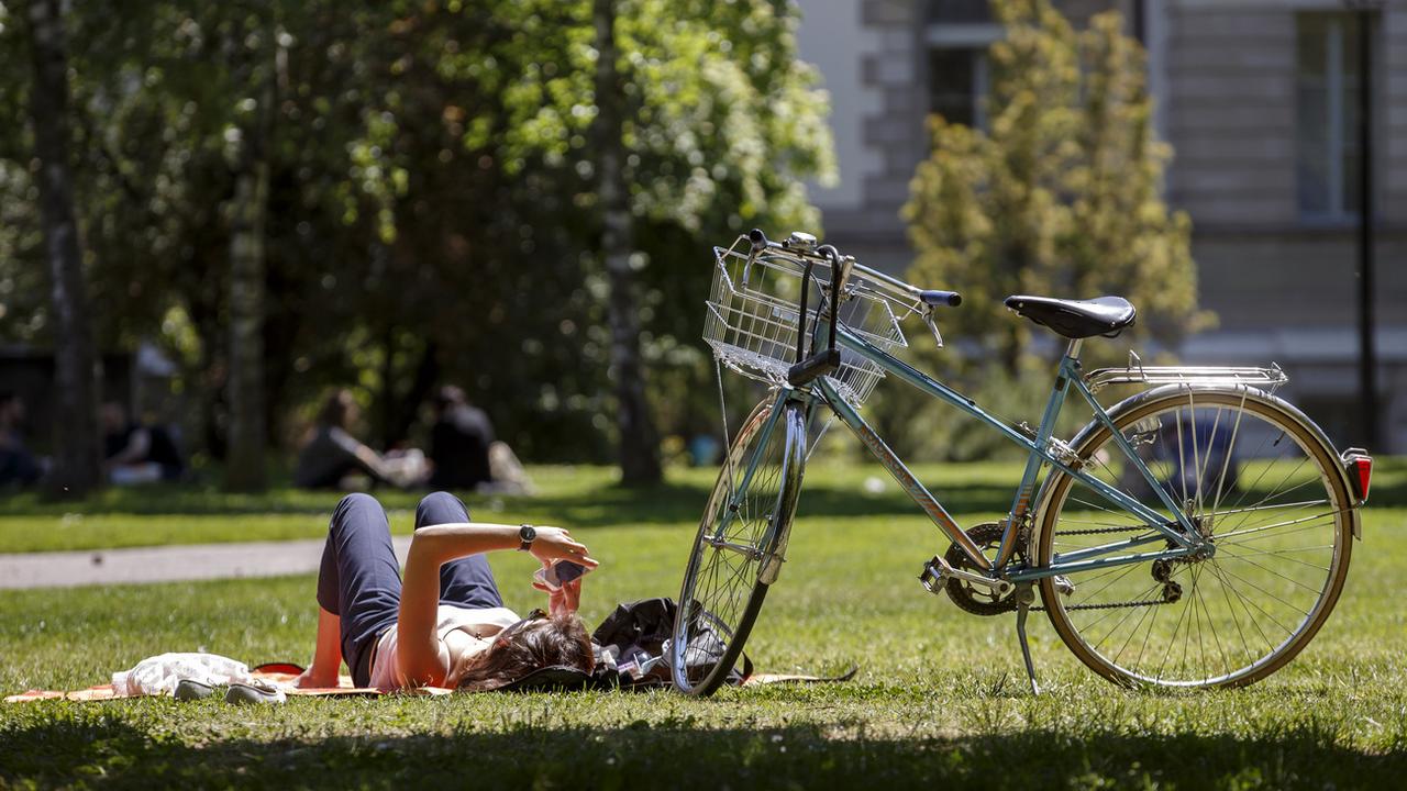 Une cycliste profite du soleil en toute quiétude, au parc des Bastions à Genève le 17 mai 2018. [Keystone - Salvatore Di Nolfi]