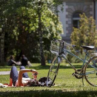 Une cycliste profite du soleil en toute quiétude, au parc des Bastions à Genève le 17 mai 2018. [Keystone - Salvatore Di Nolfi]