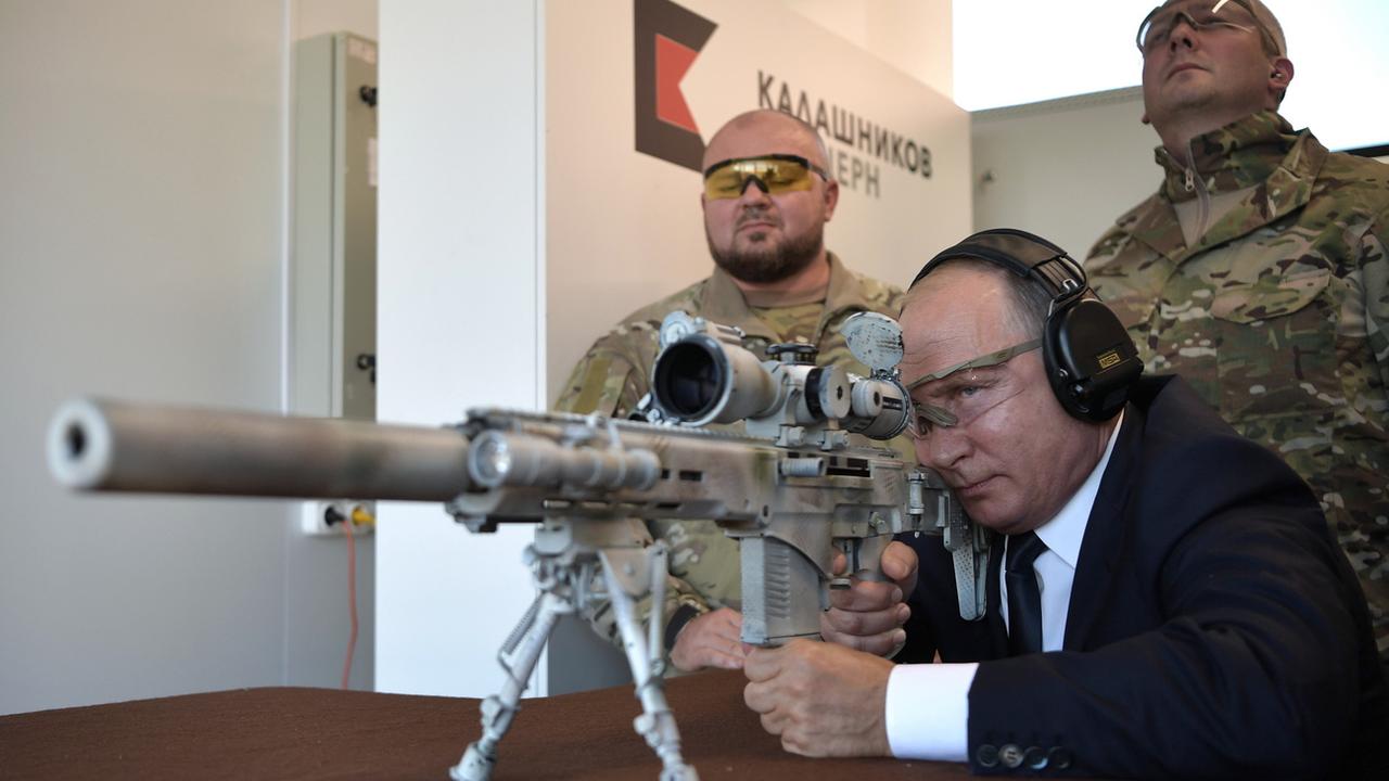 Le président russe Vladimir Poutine teste un fusil de tireur d'élite dans un parc d'attractions dédié à l'équipement militaire des troupes russes. [EPA/Sputnik/Kremlin Pool/Keystone]