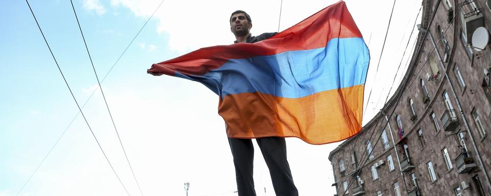 Un manifestants brandit le drapeau arménien durant un rassemblement de protestation, le 22 avril 2018. [Keystone - Aram Kirakosyan]