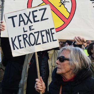 Une femme réclame une taxe sur le kérosène lors d'une manifestation à Marseille. [AFP - Boris Horvat]