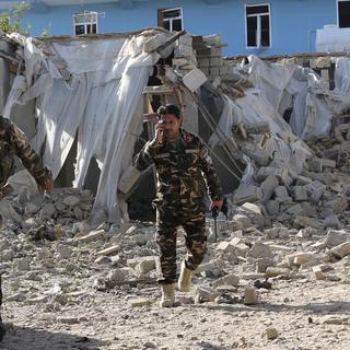 Des forces de sécurité inspectent les ruines de la base. [AP Photo - DR]
