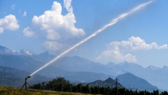 Un jet d'eau arrose un champ dans la plaine du Rhône. [Keystone - Jean-Christophe Bott]