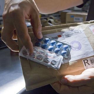 Un employé des douanes à Zurich montre un colis contenant du faux viagra. [Keystone - Alessandro Della Bella]