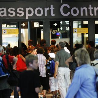 Des passagers attendant pour le contrôle des passeports à l'aéroport de Zurich. [Keystone - Steffen Schmid]
