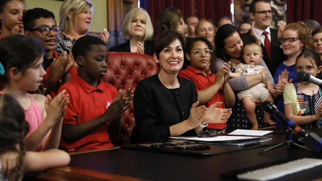 La gouverneure de l'Iowa, Kim Reynolds (centre), applaudit juste après avoir signé la loi, à Des Moines, ce 4 mai 2018. [AP Photo - CHARLIE NEIBERGALL]