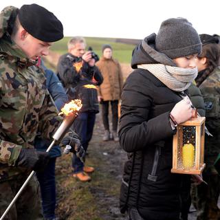 Des personnes pratiquent la cérémonie de transfert à la frontière entre l'Ukraine et la Pologne. [EPA/Keystone - Darek Delmanowicz]