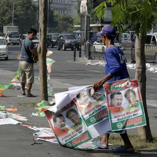 Deux hommes enlèvent le matériel de campagne suite aux élections aux Philippines. [AP/Keystone - Bullit Marquez]