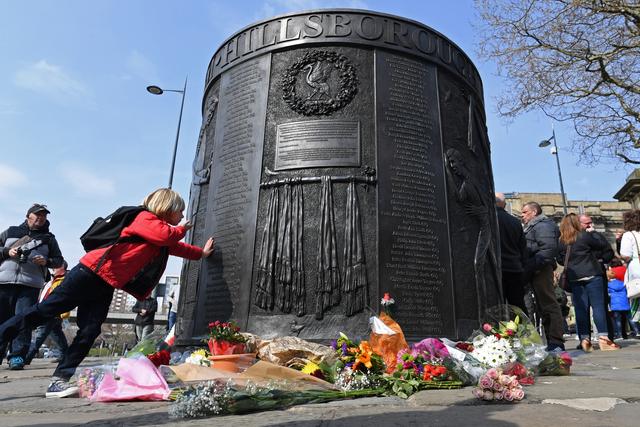 Des personnes se recueillent devant le mémorial érigé en souvenir des victimes de Hillsborough. [afp - Paul Ellis]