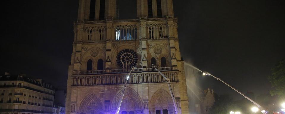 Les pompiers à l'oeuvre durant la nuit pour éteindre les derniers foyers. [AP/Keystone - Michel Euler]