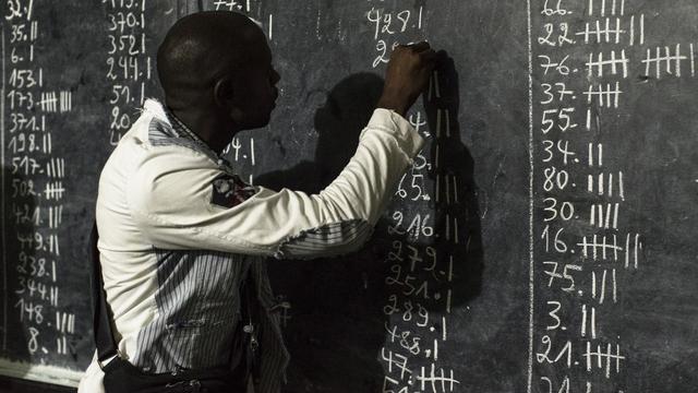 Un employé d'un bureau de vote de Kinshasa décompte les voix de l'élection présidentielle. [Keystone/EPA - Stefan Kleinowitz]