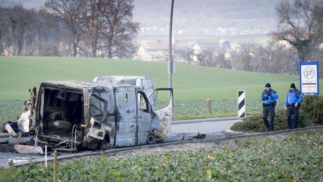 Mardi 3 décembre: des policiers observent le fourgon de transports de fonds attaqué durant la nuit à Daillens (VD) avant d'être incendié. [Keystone - Laurent Gillieron]