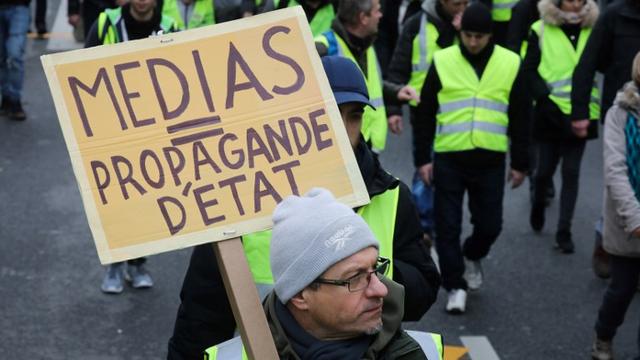 Un homme brandit une pancarte dénonçant le rôle de médias lors d'une manifestation des "gilets jaunes" le 12 janvier 2019 à Paris. [AFP - Ludovic Marin]