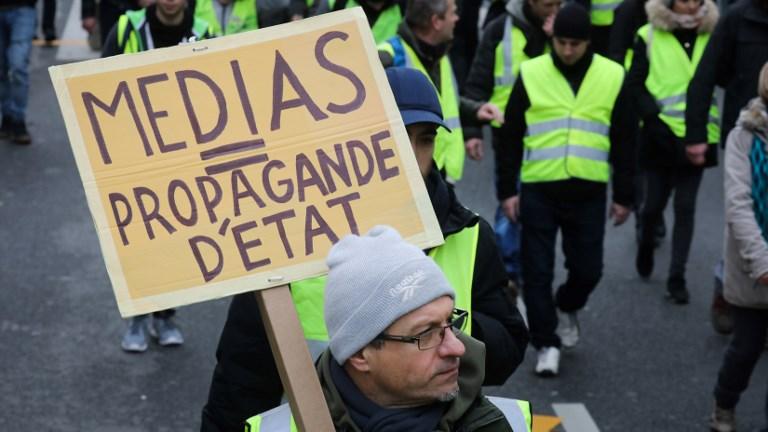 Un homme brandit une pancarte dénonçant le rôle de médias lors d'une manifestation des "gilets jaunes" le 12 janvier 2019 à Paris. [AFP - Ludovic Marin]