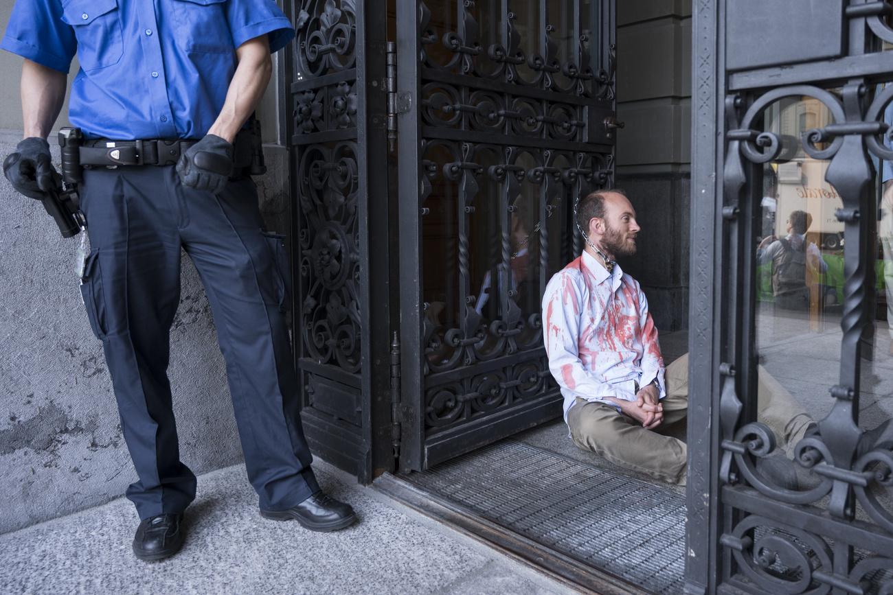 Un militant du groupe Extinction Rébellion enchaîné à la porte du Palais fédéral. [Keystone - Alessandro della Valle]