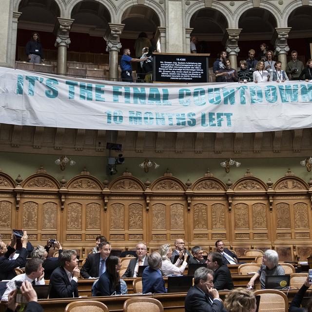 Jeudi 19 septembre; des manifestants pour le climat ont interrompu les débats au Conseil national en déroulant une banderole et en chantant depuis la tribune. [Keystone - Peter Schneider]