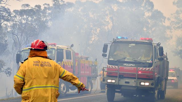 Des pompiers cherchent à sécuriser des zones résidentielles alors que des incendies font rage sur la Côte Centrale, à environ 100 kilomètres de Sydney. [AP Photo - Saeed Kahn]