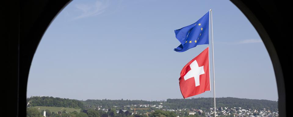 Un drapeau européen et un drapeau suisse flottent dans le vent au bord du lac de Zurich. [Keystone - Gaëtan Bally]