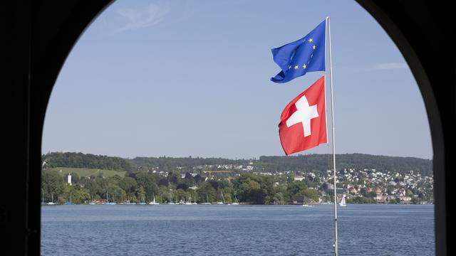 Un drapeau européen et un drapeau suisse flottent dans le vent au bord du lac de Zurich. [Keystone - Gaëtan Bally]