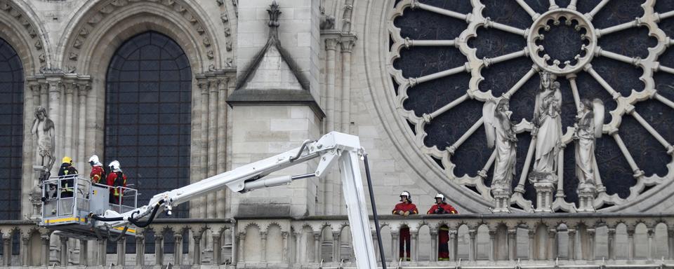 Des pompiers s'activaient encore mardi matin sur la façade de Notre-Dame de Paris. [AP Photo - Thibault Camus]