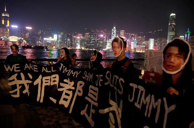 Des manifestants portent un masque représentant le portrait de Jimmy Sham. Leur banderole annonce: "Nous sommes tous Jimmy Sham", Hong Kong, le 18 octobre 2019. [Reuters - Umit Bektas]