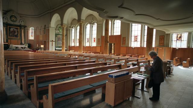 Une femme dans une église catholique à Zurich. [Keystone - Gaetan Bally]