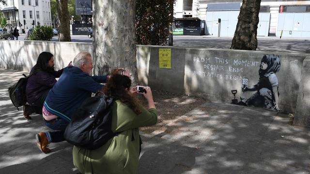 Des curieux photographient le nouveau graffiti attribué à l'artiste Banksy près de Marble Arch, à Londres. [Keystone - EPA/ANDY RAIN]