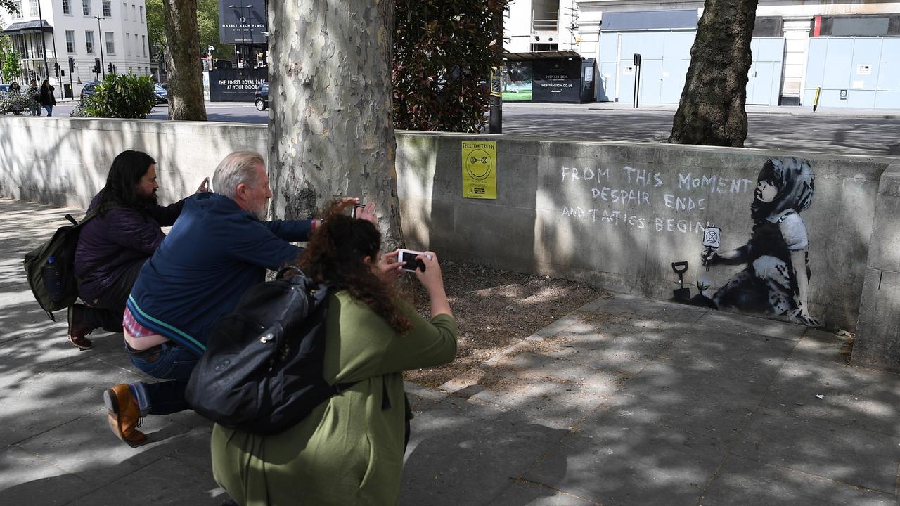 Des curieux photographient le nouveau graffiti attribué à l'artiste Banksy près de Marble Arch, à Londres. [Keystone - EPA/ANDY RAIN]