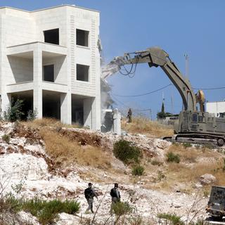 Une pelleteuse israélienne détruit un immeuble du village palestinien Sur Baher. [EPA - Abed Al Hashlamoun]