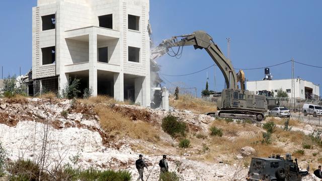 Une pelleteuse israélienne détruit un immeuble du village palestinien Sur Baher. [EPA - Abed Al Hashlamoun]